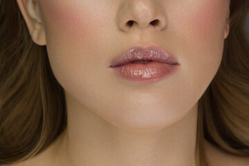 Sexual full lips. Natural gloss of lips and woman's skin. The mouth is closed. Increase in lips, cosmetology. Pink lips and long neck. Gentle pure skin and wavy blonde hair.