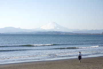 Enoshima, Kanagawa, Japan, Beautiful Fuji mountain or Fuji-San and sea, beach view in sunny blue sky day. Unknow girl walk along the beach and sea wave in moving.