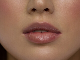 Naklejka premium Sexual full lips. Natural gloss of lips and woman's skin. The mouth is closed. Increase in lips, cosmetology. Pink lips and long neck. Gentle pure skin and wavy blonde hair.