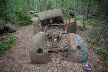 Old cars in Sscrapyard in forest in Ryd Sweden