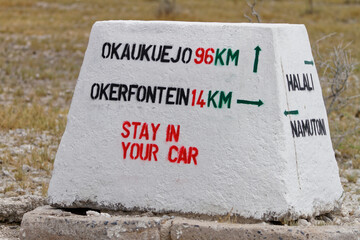ETOSHA NATIONAL PARK, NAMIBIA - Nov 22, 2015:A signpost with text Stay in your car on a road in the Etosha National Park, Namibia