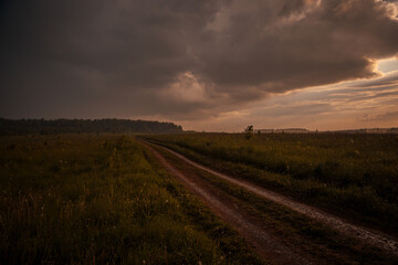 Obraz premium beautiful evening sky with heavy rain clouds over a road wet from rain