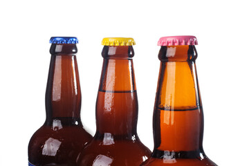 Row of brown beer bottles over white background. Beer with colored caps. Close up view of drinks with copy space.