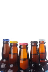 Row of brown beer bottles over white background. Beer with colored caps. Close up view of drinks with copy space.