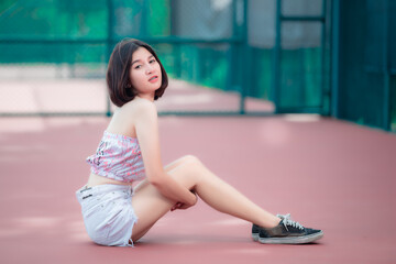 Fototapeta na wymiar Portrait of hipsters girl pose for take a photo at tennis court,Thailand people,Lifestyle of modern thai woman