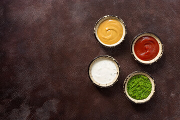Collection of various sauces in the bowl: tomato, pesto, creamy with greens and mustard on a dark rustic background. Top view, copy space.