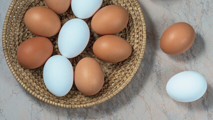 several fresh chicken eggs in a straw basket on a wooden background. Healthy eating concept.