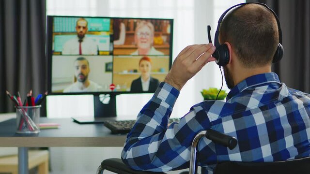 Businessman with headphones in wheelchair during video call. Handicapped invalid paralysed freelancer, immobilized entrepreneur working from home, ilness and disability
