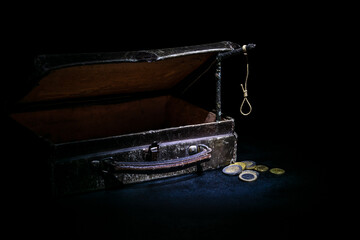 A small old suitcase and a scaffold, a few coins in a low key. Concept: poverty, lack of money, frustration and death.