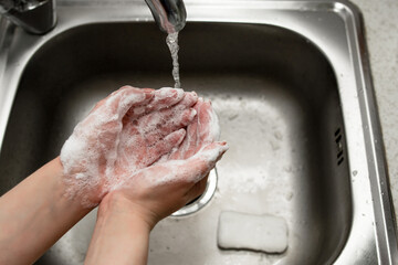 girl washes hands with soap in the wash basin