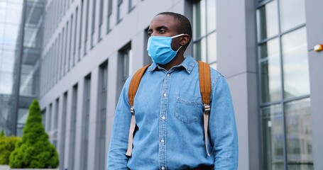 Portrait of young African American handsome and cheerful man taking off medical mask and smiling after coronavirus gone. End of pandemic concept Happy male throwing off respiratory protection.