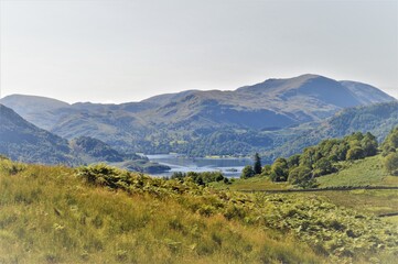 mountain landscape in the Lake District mountains with lake and speedboat in the distance 