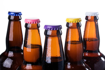 Brown beer bottles over white background. Beer with colored caps. Close up view of drinks with copy space.