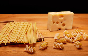 Raw pasta and cheese on a wooden table, healthy food concept
