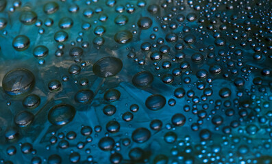 Abstract turquoise-malachite background of drops and droplets. Close up. Illuminated by the bright...