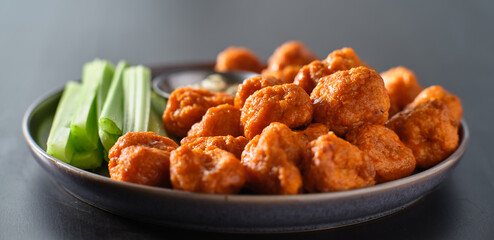 plate of boneless chicken wings with buffalo sauce and celery sticks