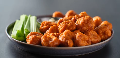 Foto op Canvas plate of boneless chicken wings with buffalo sauce and celery sticks © Joshua Resnick