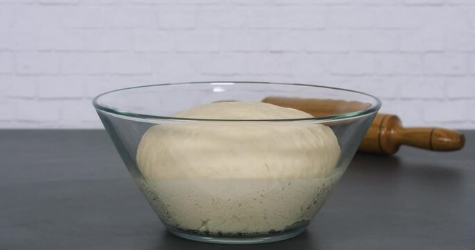 Time lapse. The dough rise . Yeast dough rising in the glass bolw on the gry marble on white background
