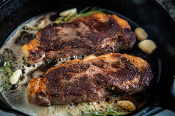 cooking new york strip steak on skillet pan