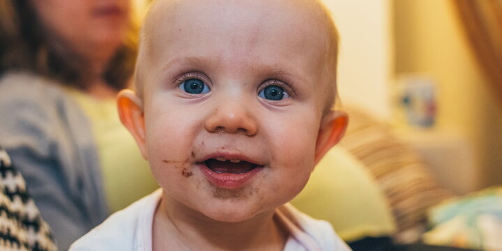 Small girl with chocolate smeared all over her face. Funny faces with small child eating chocolate. Small boy smeared with chocolate all over his face. Kid with the funny face. Chocolate and smile