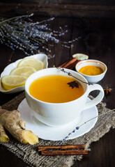 turmeric tea with cinnamon and ginger in a white cup on wooden table 
