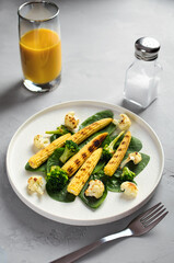 grilled vegetables and juice on a light stone background, dietary vegetarian snack babycorn, healthy low-calorie food, vertical frame