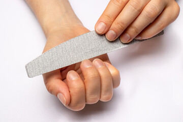 Manicure at home, sawing nails with a sawn-off and giving a square shape to the nail plate. Caring for nails. - obrazy, fototapety, plakaty