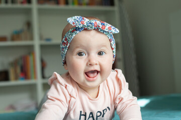 Cute baby girl with hairband (ribbon), smiling, laughing.