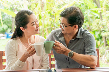 Happy smiling middle aged couple holding the coffee cup in the garden at home.  Good relationship, together,Morning.   