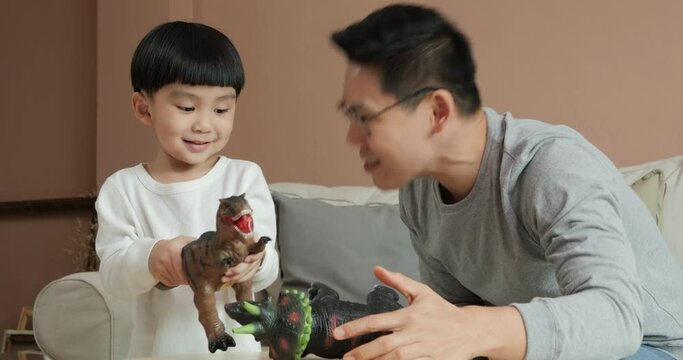 Father And Son Playing Dinosaur Toy Together At Home. Little Boy Try To Fight With Father By T-rex Toy.