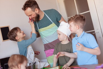 Obraz premium happy father with children cooks on paternity leave in the kitchen