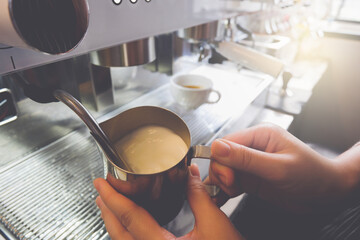 Close up shot of a barista steam milk to make hot drinks.