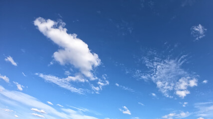 Naklejka na ściany i meble White clouds on a blue sky as a background. Sunny weather.