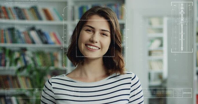 Portrait of young pretty Caucasian girl in library with face recognition technology on. Augmented reality. Biometric facial recognition. Close up of female smilingh to camera. 3D scanning.