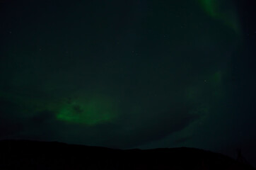 faded green aurora borealis on cloudy night sky