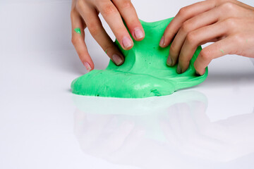 Child plays with green slime over light gray background.