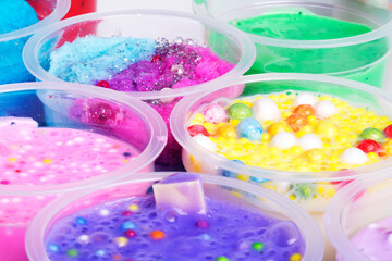 Various bows of colored slime with colorful dots over light gray background.
