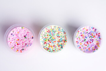 Boxes of colored slime with decorations over light background. Children fun and leisure activities. 