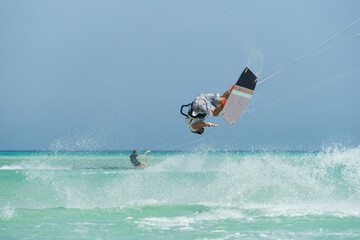 kiter does a difficult trick on a background of transparent water and blue sky