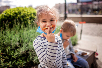 New normal reality, stay safe in street cafe, father with kids in medical masks eating fast food