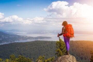 Naklejka premium Adventurous Girl hiking with a backpack on top of a mountain with a beautiful Canadian Nature Background. Taken in Bowen Island, near Vancouver, British Columbia, Canada.