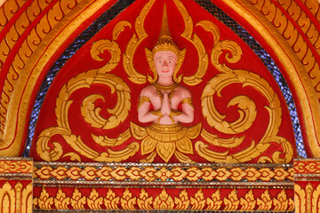 Fototapeta na wymiar Buddha image fresco on a red and golden painted wall of a wat in Siamese Lao PDR, Southeast Asia