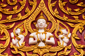 Golden buddha image frescoes on a red wall of a wat in Siamese Lao PDR, Southeast Asia