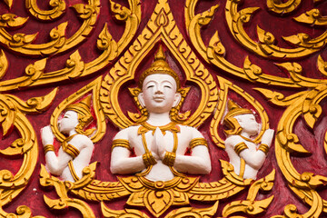 Fototapeta na wymiar Golden buddha image frescoes on a red wall of a wat in Siamese Lao PDR, Southeast Asia
