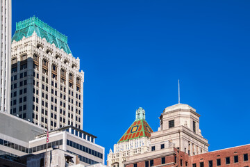 View of rooftops of downtown Tulsa Oklahoma -mixture of Art Deco and modern buildings with an American flag against very clear blue sky