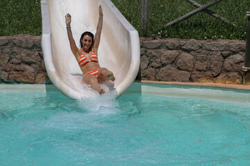 Girl in bikini having fun when falling down water slide in water park