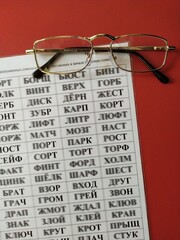 A table of reading words and gold-rimmed glasses on a red background