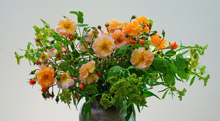 An orange and green bouquet with orange garden roses and yellow lovage flowers