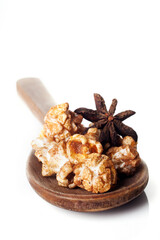 Wooden spoon with gourmet anise popcorn isolated on white background.