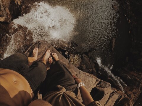 Couple of two lovers stand on the top of waterfall shoot legs and waterfall stream pov. Traveling together  in India Asia